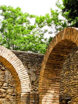 Stone arches with lush greenery in Ronda, Andalusia, Spain captured in bright daylight.