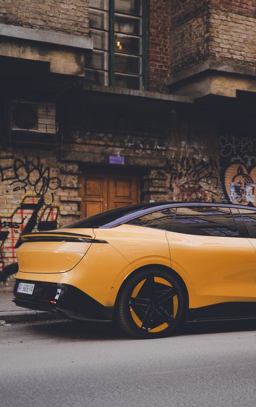 Free A modern yellow car is parked against an urban graffiti street wall, showcasing sleek design. Stock Photo