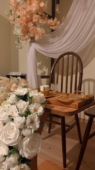 Beautiful wedding reception setup with white and peach florals and wooden chairs. - Fotografer Sidoarjo