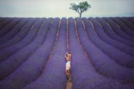 一位戴着帽子的女人在明亮的天空下，欣赏着一望无际的薰衣草田