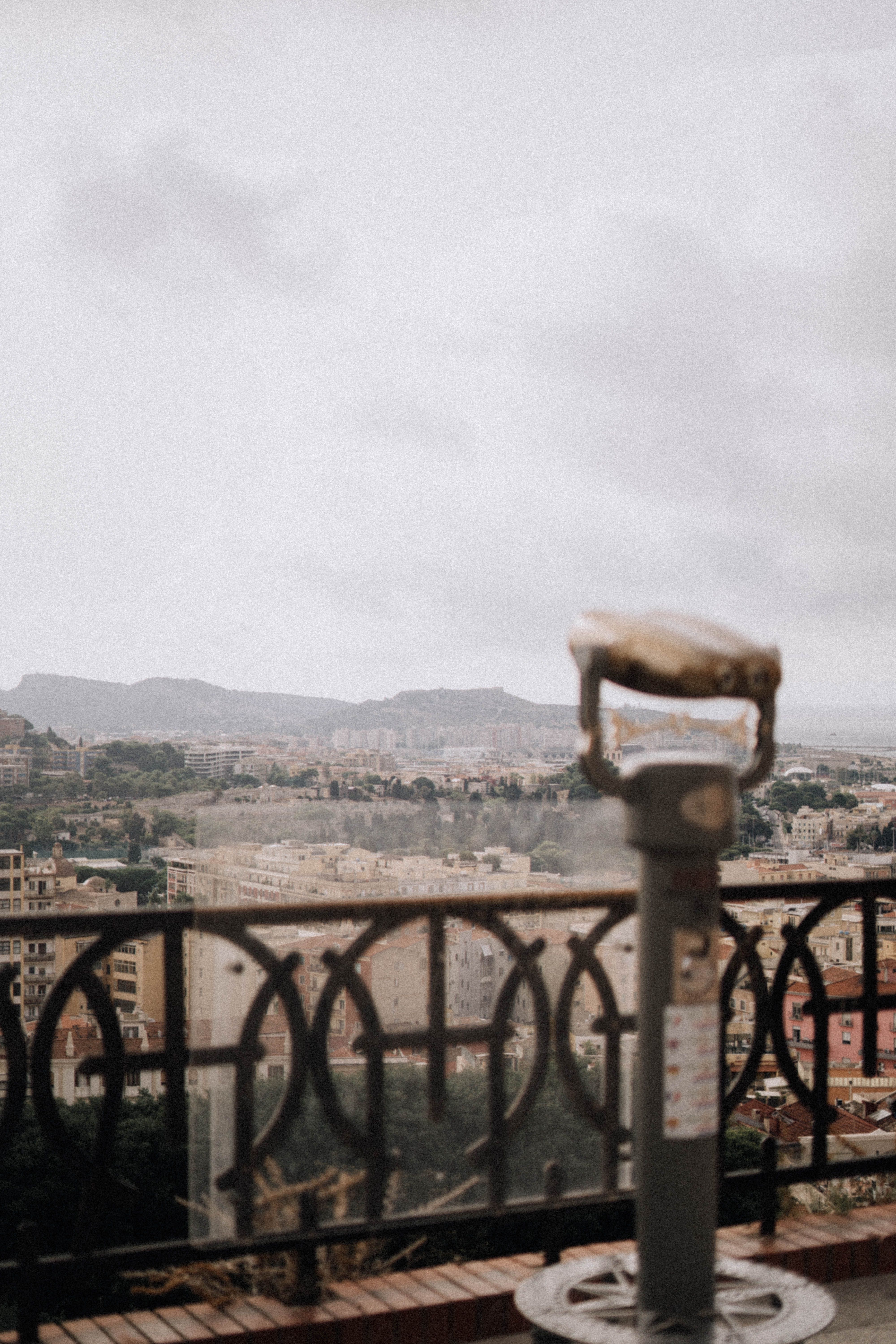 Urban landscape view featuring city skyline through tourist binoculars on a cloudy day.