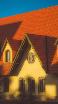 Picturesque cottage with distinctive red roof and warm sunlight, creating a cozy ambiance.