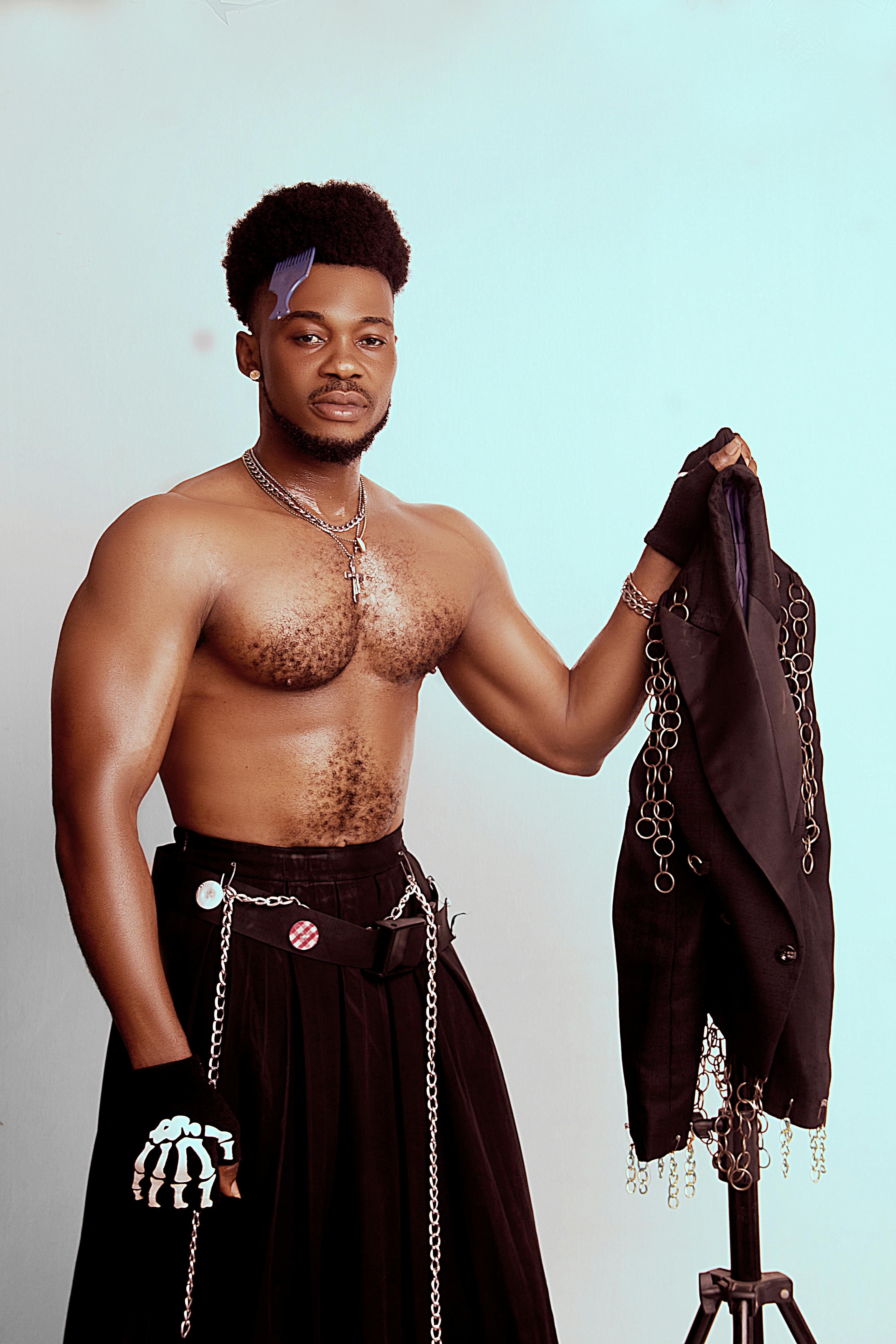 Artistic portrait of a fashionable man holding a jacket with chain details, showcasing unique style.