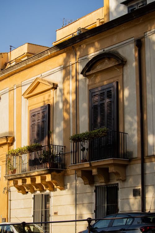 Free Sunlit European building facade with classic balconies and warm tones. Stock Photo