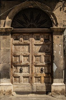 Vintage wooden door with ornate details and archway, perfect for historical context.