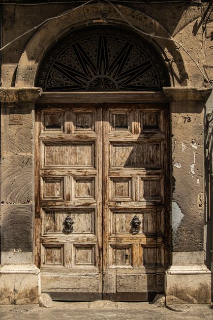 Vintage wooden door with ornate details and archway, perfect for historical context.