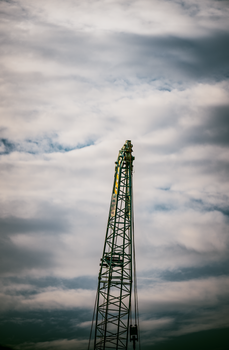 A construction crane stands tall against a cloudy sky in Bangkok, Thailand.