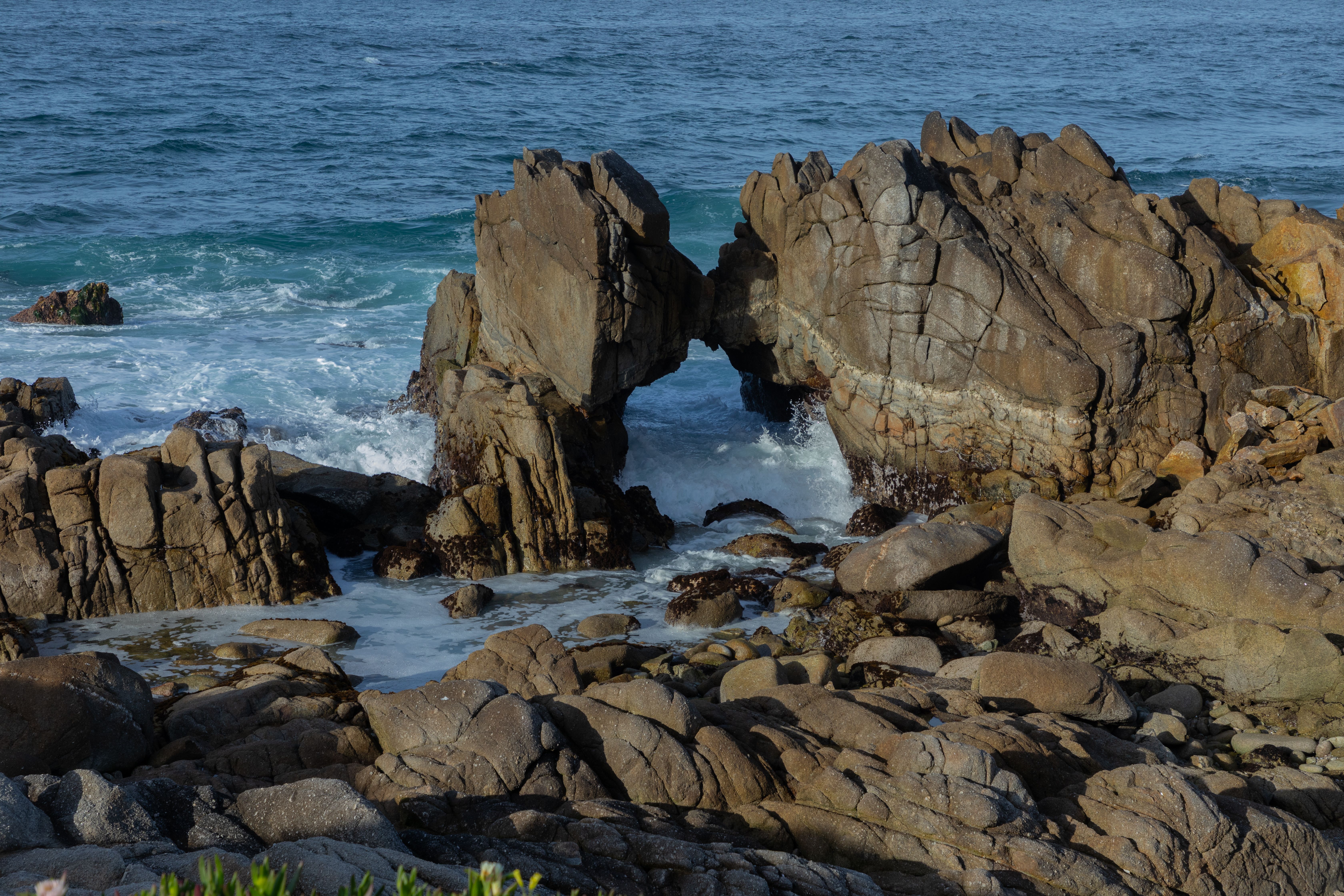 Dramatic coastal rock formation and crashing waves in Monterey, California.