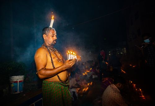 Free Man performing candle ritual during a night religious festival with candles and spiritual aura. Stock Photo