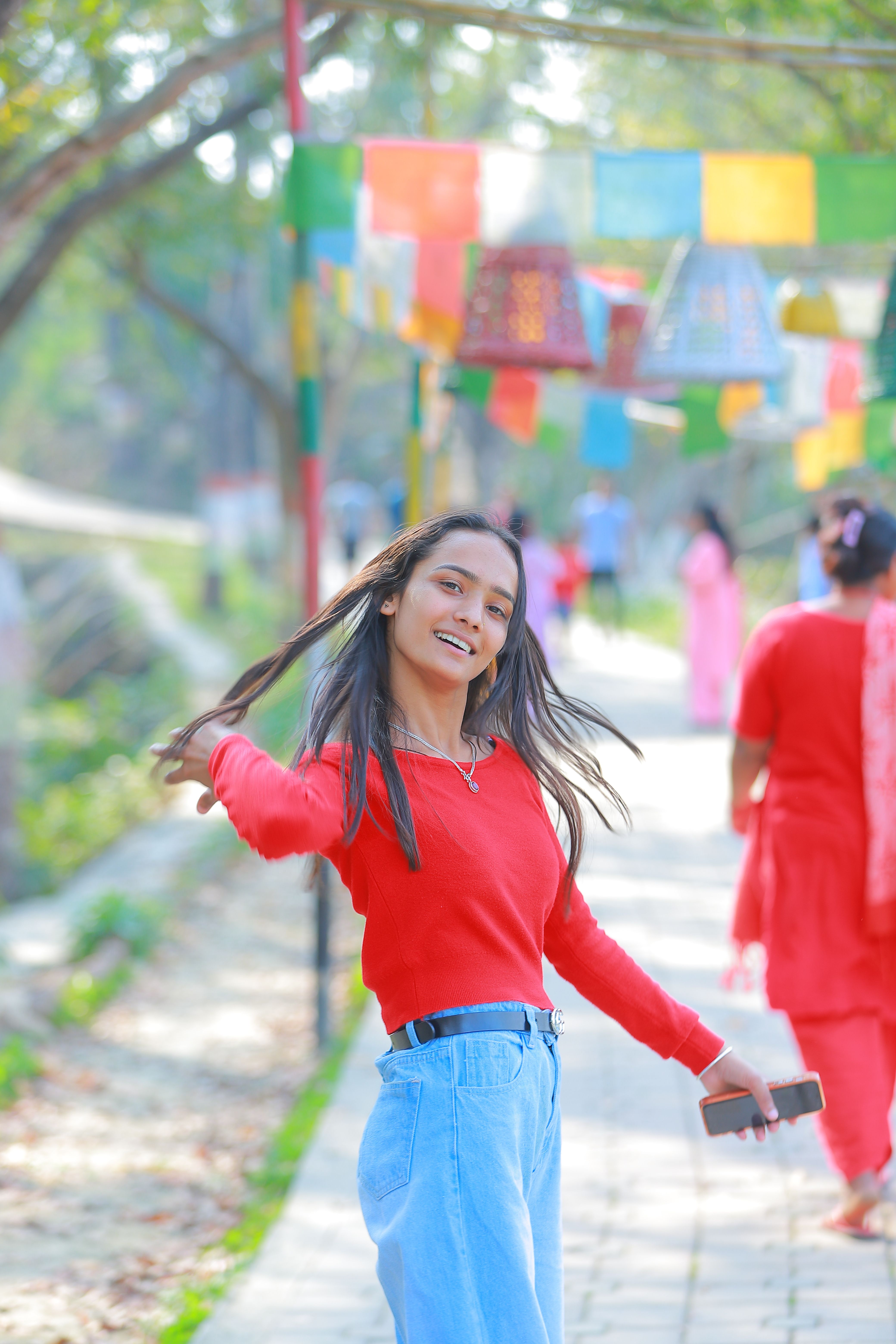 A cheerful woman in red enjoys a sunny day outdoors, surrounded by colorful flags.