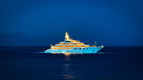 Free A luxury yacht illuminated beautifully against the dark ocean night, exuding opulence. Stock Photo