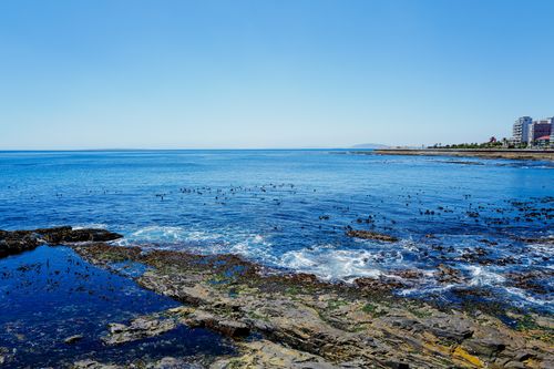Free Scenic coastal view with rocky shoreline and vibrant blue ocean under a clear sky. Stock Photo