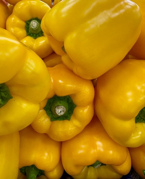 Free Vibrant close-up of a stack of fresh yellow bell peppers showcasing their bright color and texture. Stock Photo
