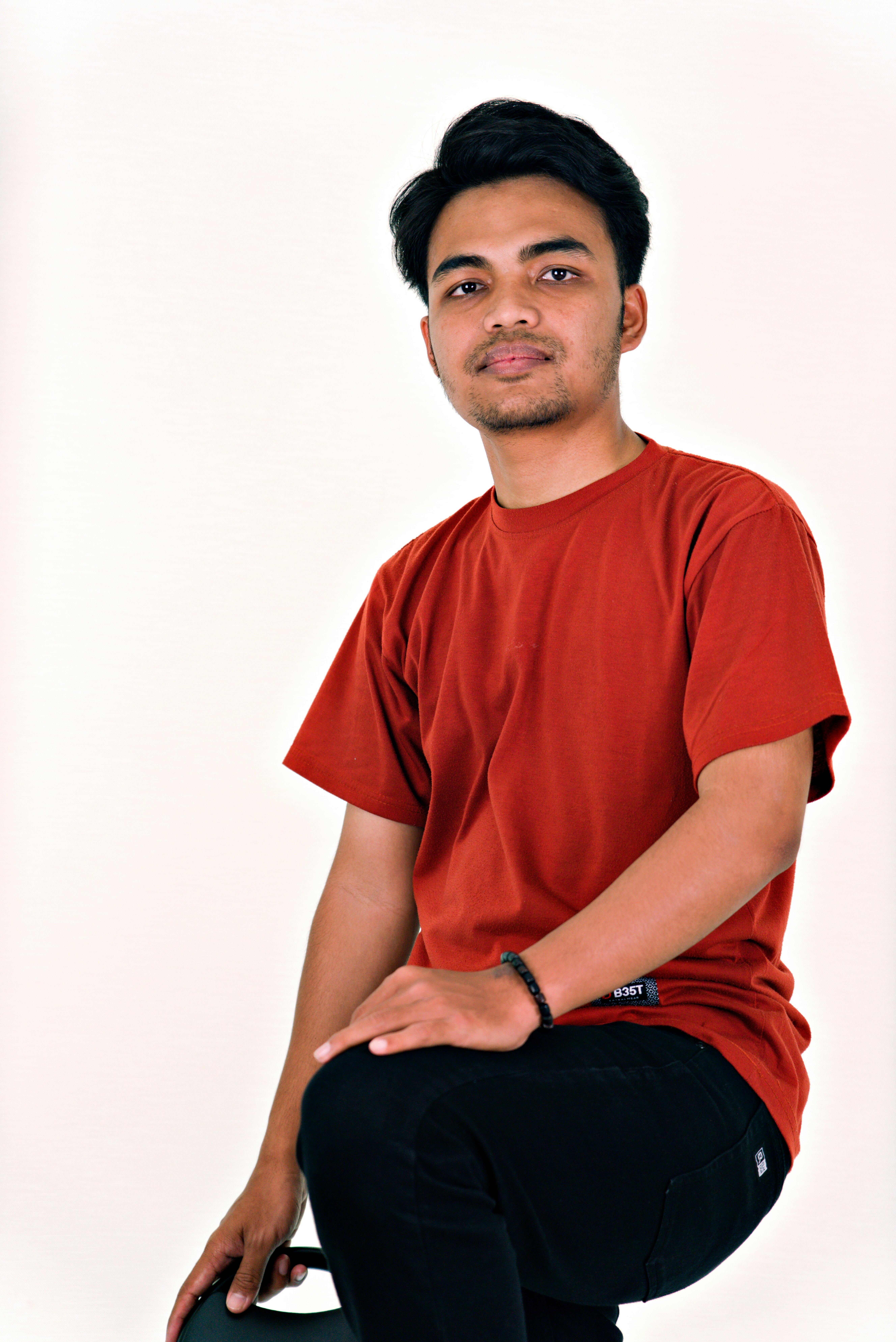 Portrait of a young adult male in a red shirt against a white background.