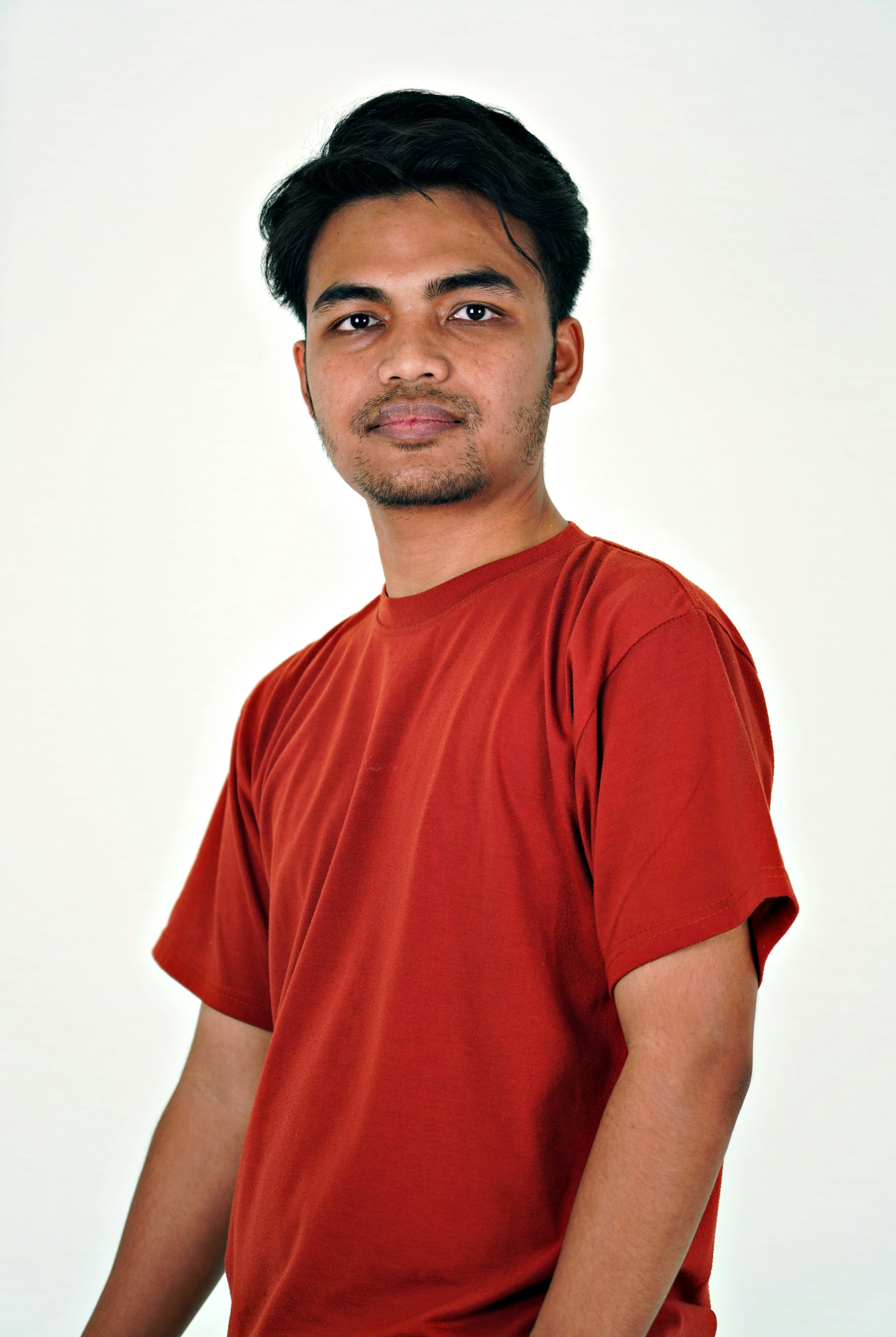 Studio portrait of a young adult wearing a red t-shirt, neutral background.