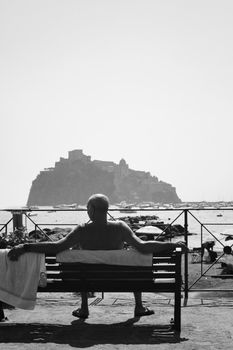 A thoughtful moment of relaxation on Ischia Island with Castello Aragonese in the background.
