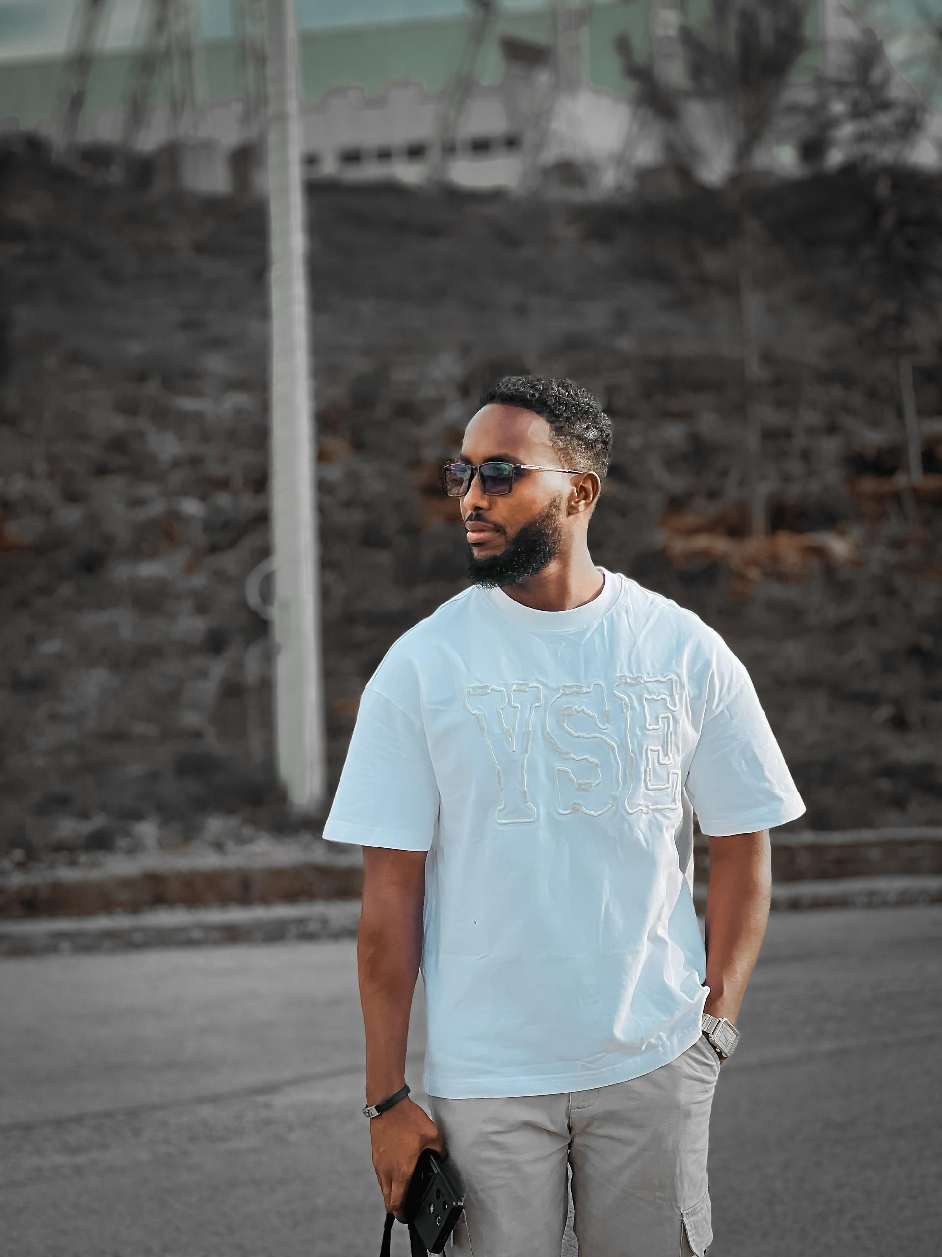 Outdoor shot of a fashionable man wearing sunglasses and casual clothing.