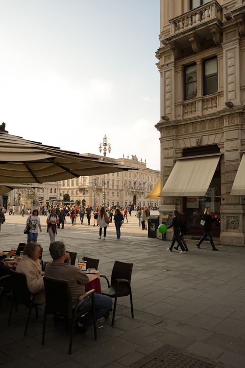 Free A lively scene captures people socializing at an outdoor cafe in a European city square. Stock Photo