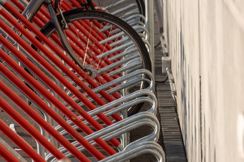 Bicycle parking area with striking red and silver racks, featuring closely arranged bike wheels.