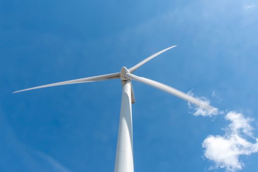 A powerful wind turbine stands tall against a bright blue sky, symbolizing renewable energy.