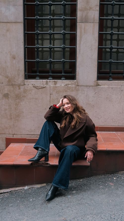 Free A woman in stylish attire sitting outside, enjoying a casual moment in İstanbul, Türkiye. Stock Photo