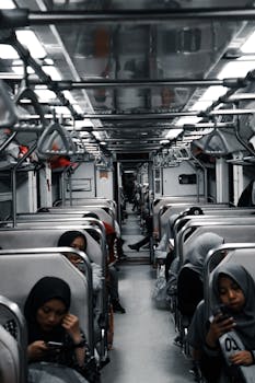 Passengers seated in a subway train, absorbed in their mobile devices on a daily commute.