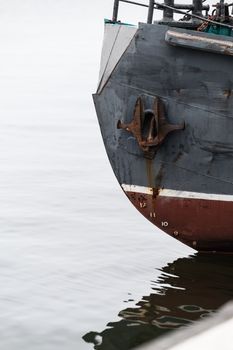 Close-up of a rusty ship bow in Baltiysk, Kaliningrad Oblast, Russia, against calm water.