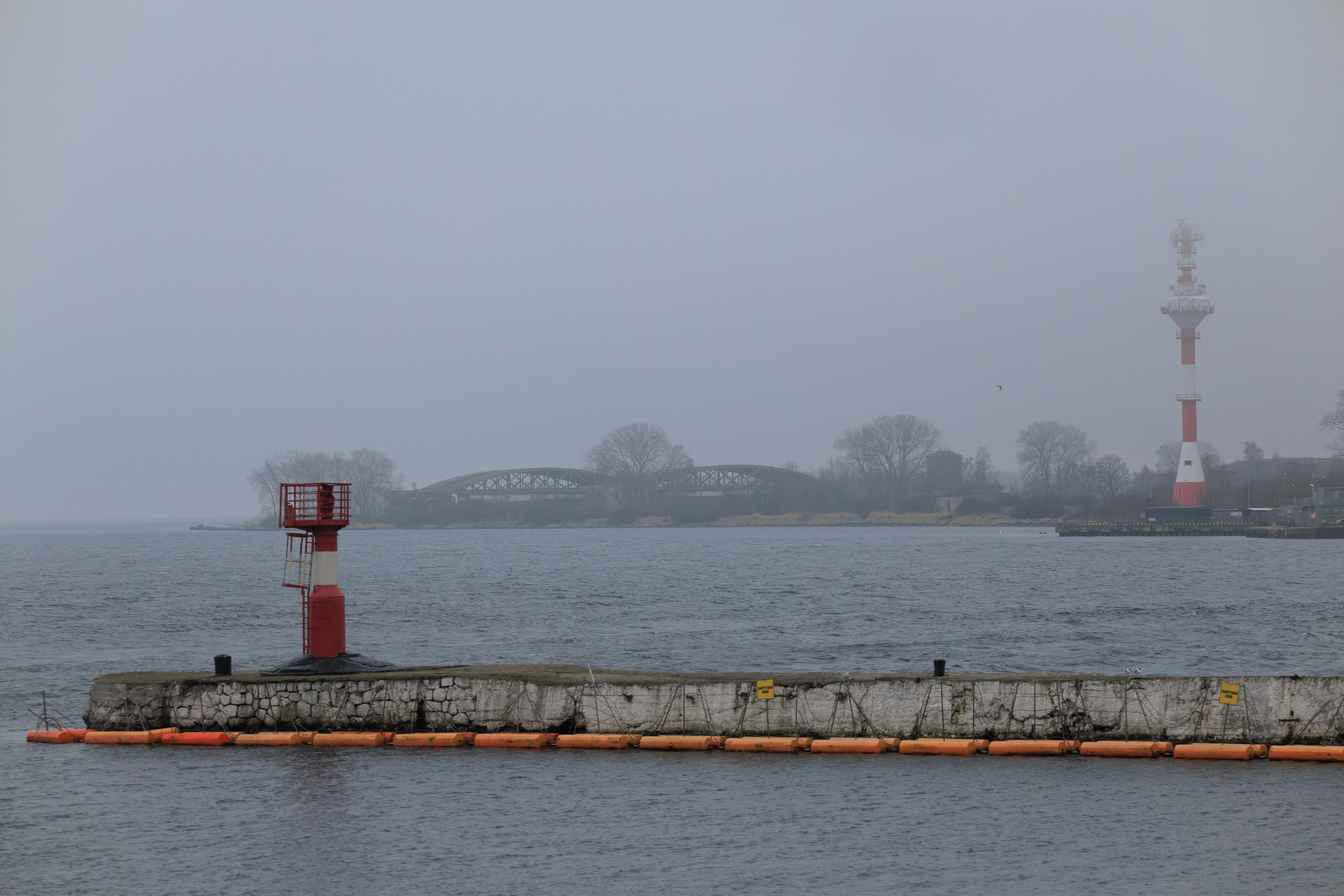 Overcast day at Baltiysk waterfront showing buoys, beacon, and lighthouse. — Trójmiasto