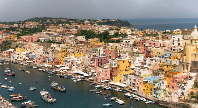 A stunning aerial view of Procida, Italy, showcasing colorful buildings and boats in a scenic coastal setting.
