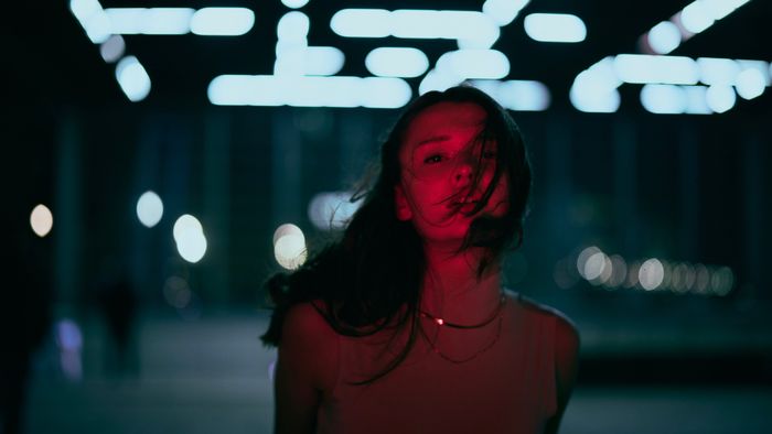 A creative portrait of a woman illuminated by neon lights with a dramatic red glow., by Finn Semmer on Pexels