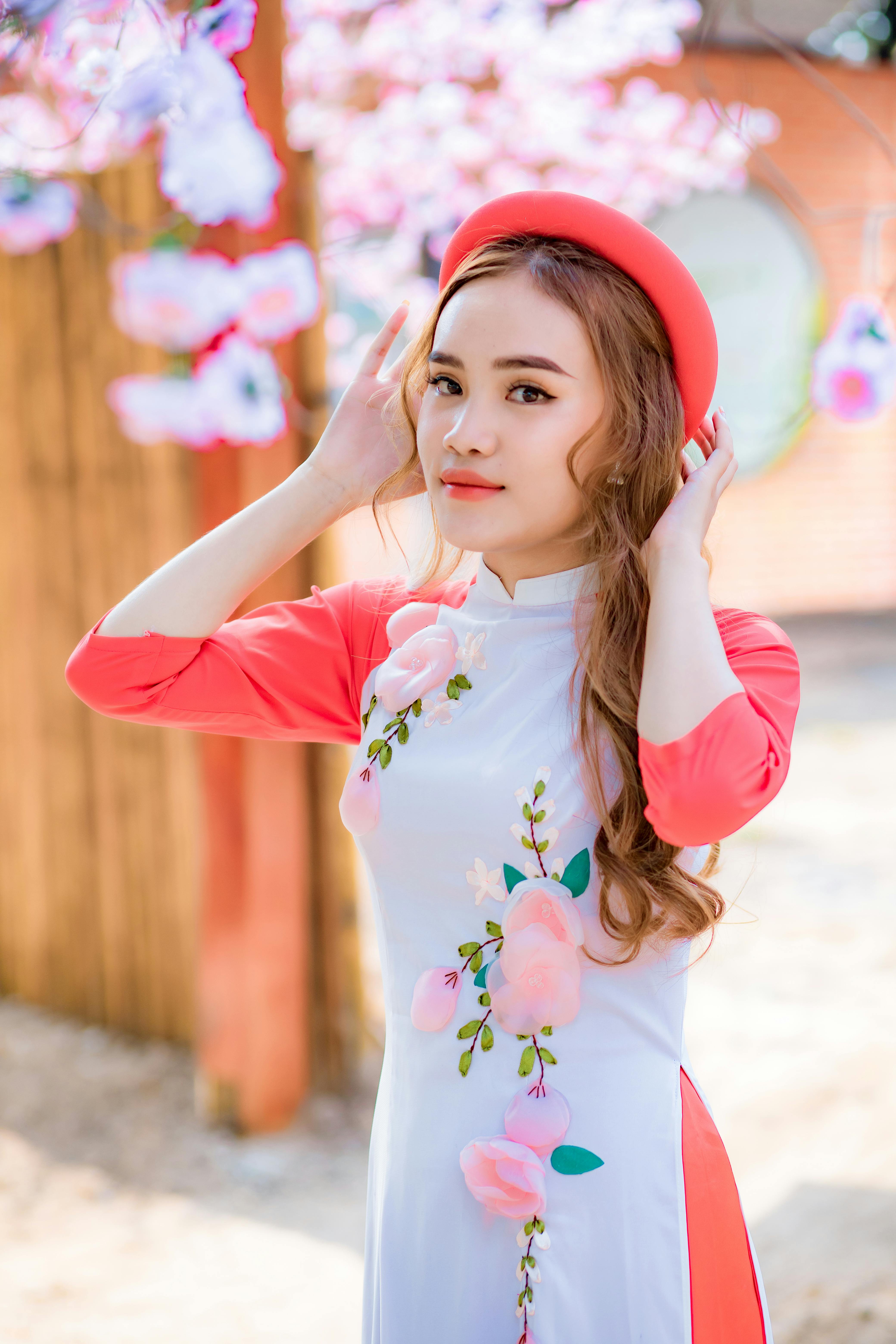 美丽的亚洲女子身着传统花卉敖戴，在户外摆出欢乐的表情