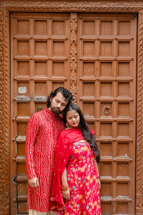 Free A loving couple in vibrant traditional attire poses by a decorative wooden door in Varanasi. Stock Photo