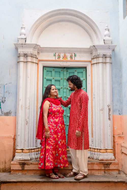 Free A couple dressed in vibrant traditional attire stands in front of a historic doorway in Varanasi, capturing a moment of elegance and love. Stock Photo