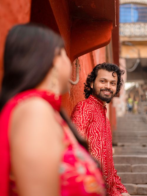 Free A loving couple in red outfits captured on the historic steps in Varanasi, India. Stock Photo