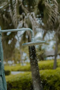 Refreshing outdoor shower with flowing water in a tropical garden backdrop.