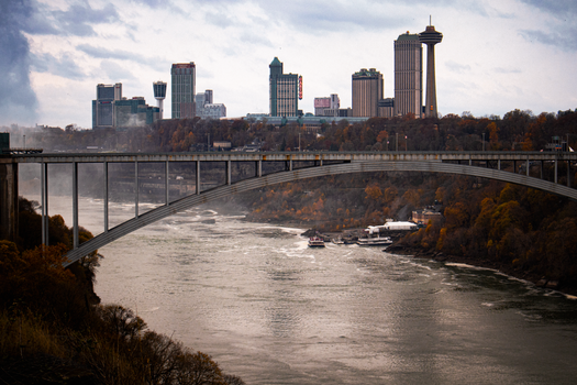 Dramatic fall view of Rainbow Bridge over the Niagara River with city skyline.