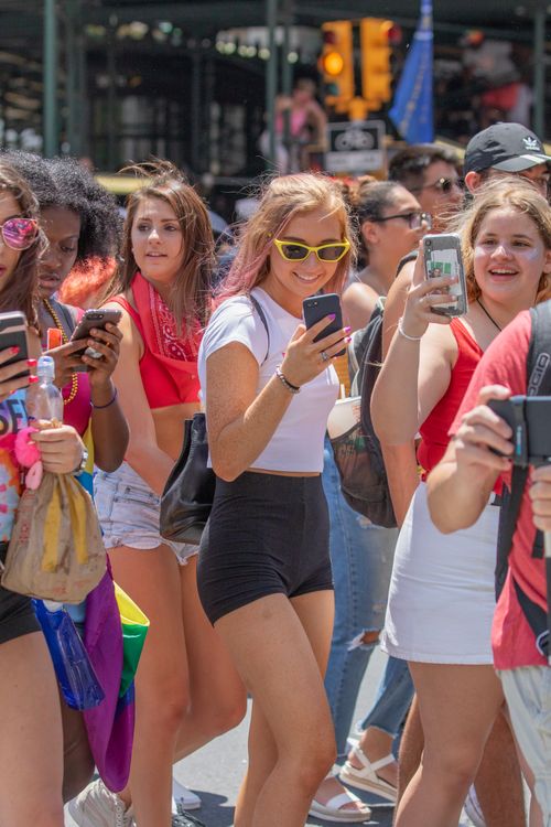 Free A group of young adults using smartphones at a lively outdoor event in sunny weather. Stock Photo