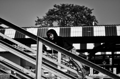 Free Black and white side view of barefoot boy in hoodie rolling down railing while spending summer time outdoors Stock Photo