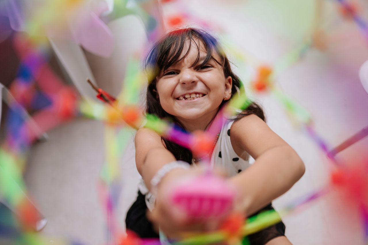 smiling child engaged with a colorful toy in an indoor setting conveyi
