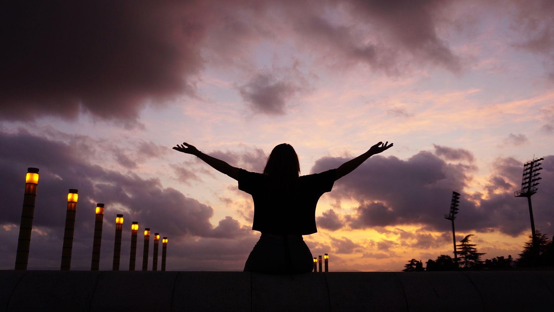 Silhouette of a person with arms outstretched against a dramatic sunset sky, symbolizing freedom and nature.