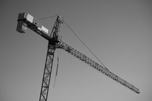 Free Black and white image of a construction crane set against a clear sky, capturing industrial design. Stock Photo