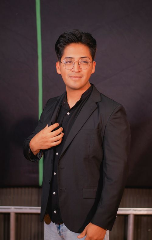 Free Portrait of a young man in formal attire against a dark backdrop, exuding confidence. Stock Photo