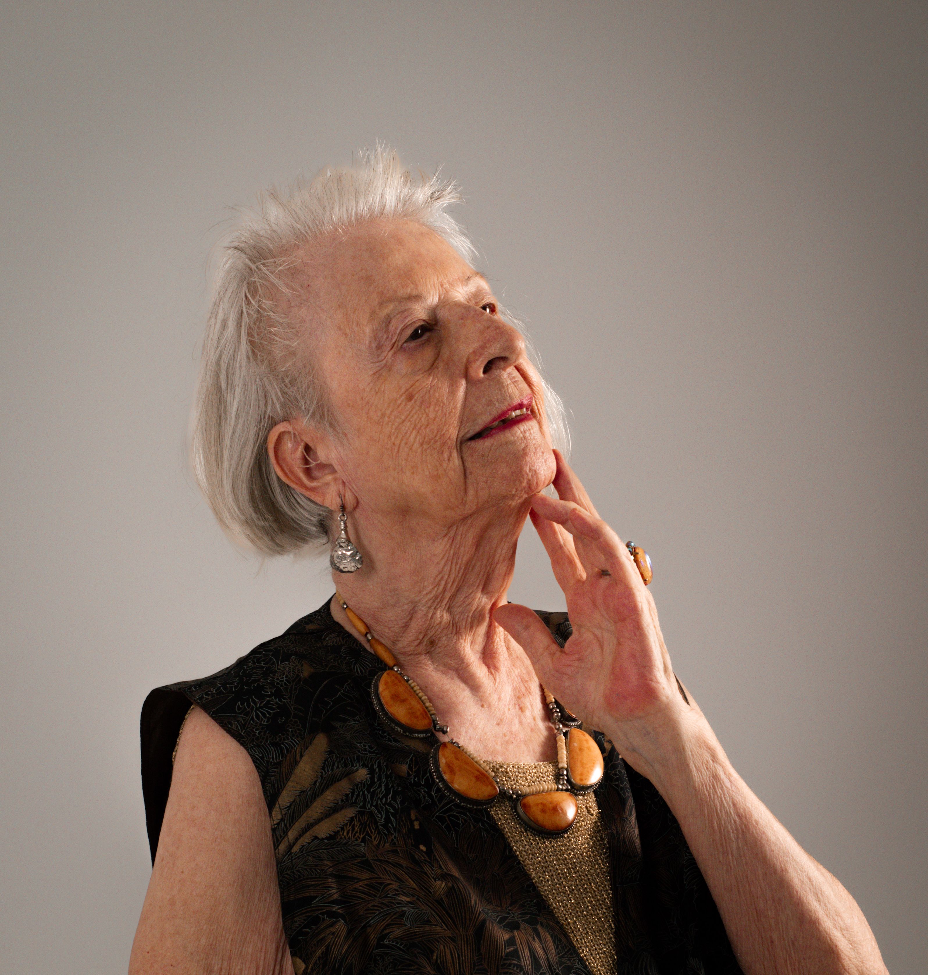 An elegant senior woman poses gracefully in a photo studio, showcasing timeless style and fashion.