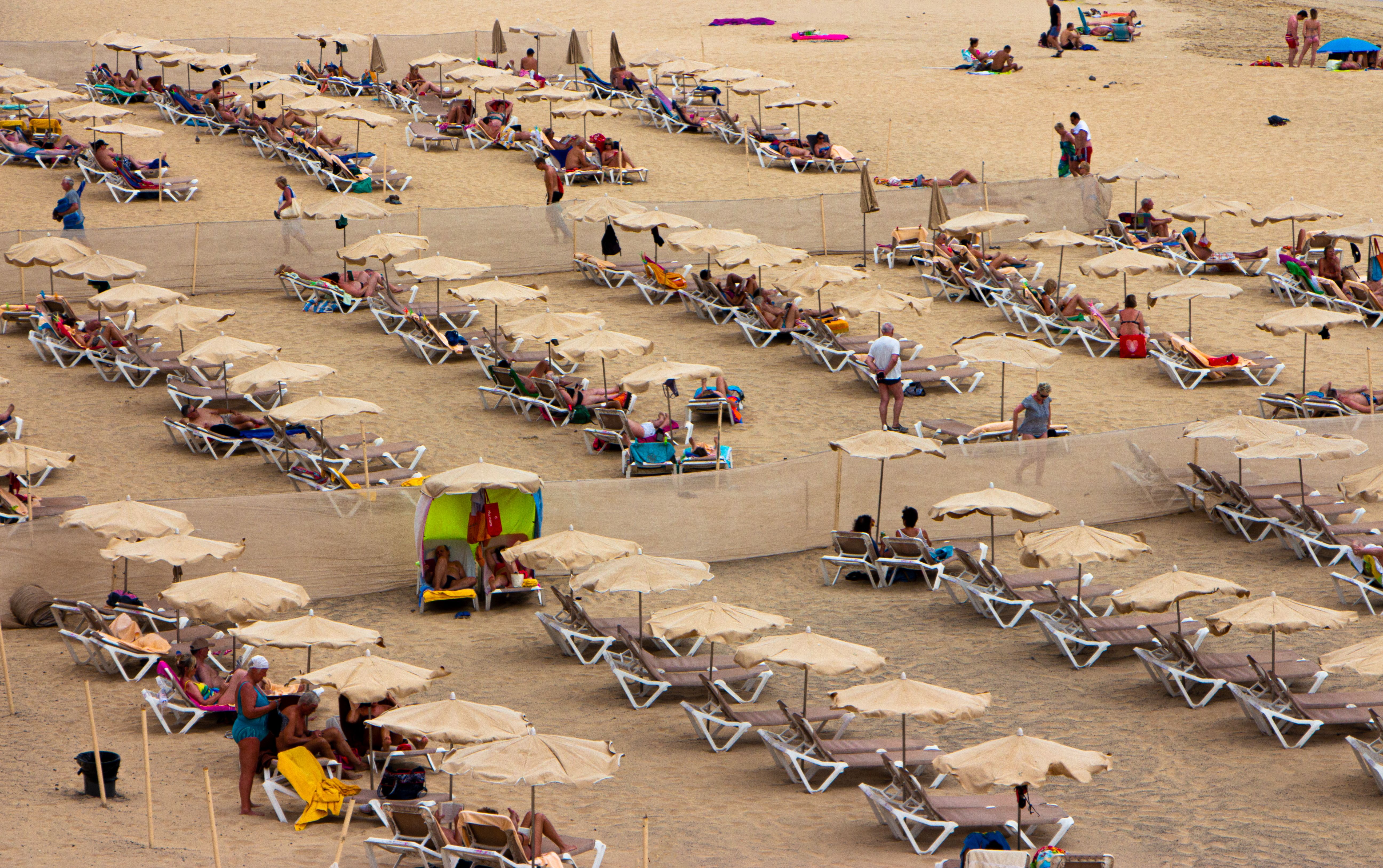 Cypriot families with picnic tables and parasols crowding a beach on a summer public holiday