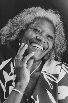 A joyful close-up portrait of a senior woman with a warm smile, captured in monochrome.