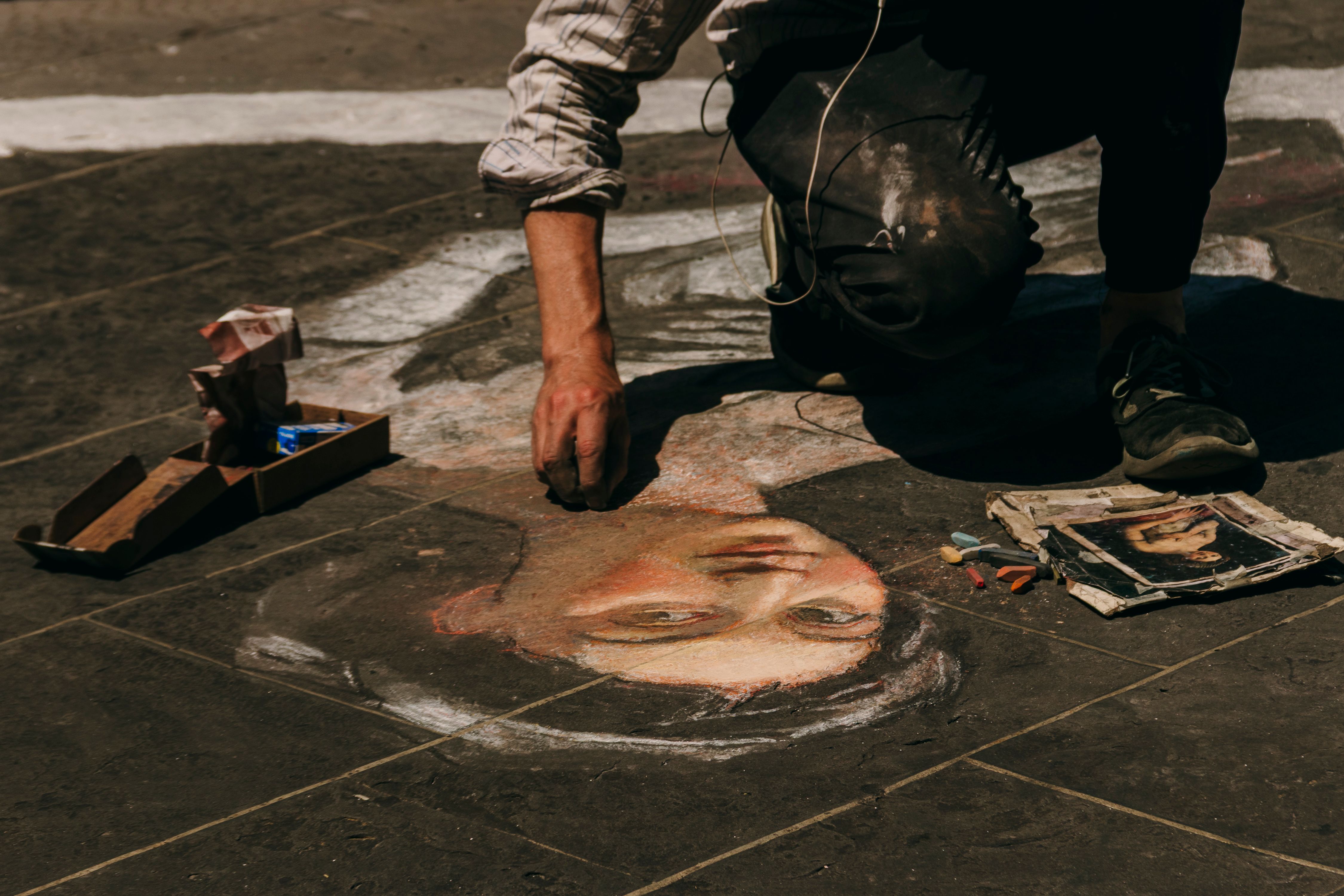 Street artist creating a detailed chalk portrait on the pavement in Florence, Italy.