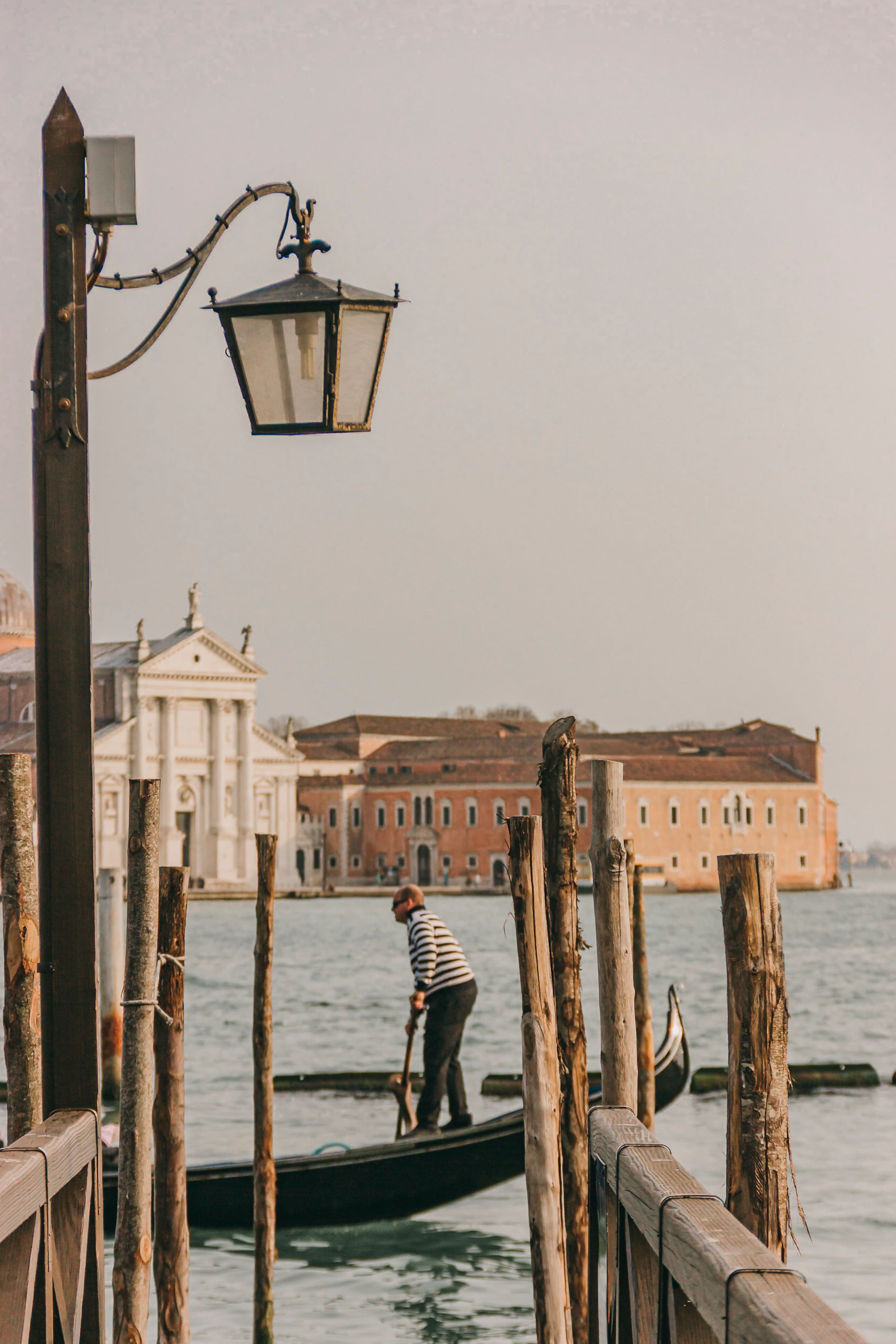 A gondolier in Venice's iconic canals with historical architecture in the background during daylight.