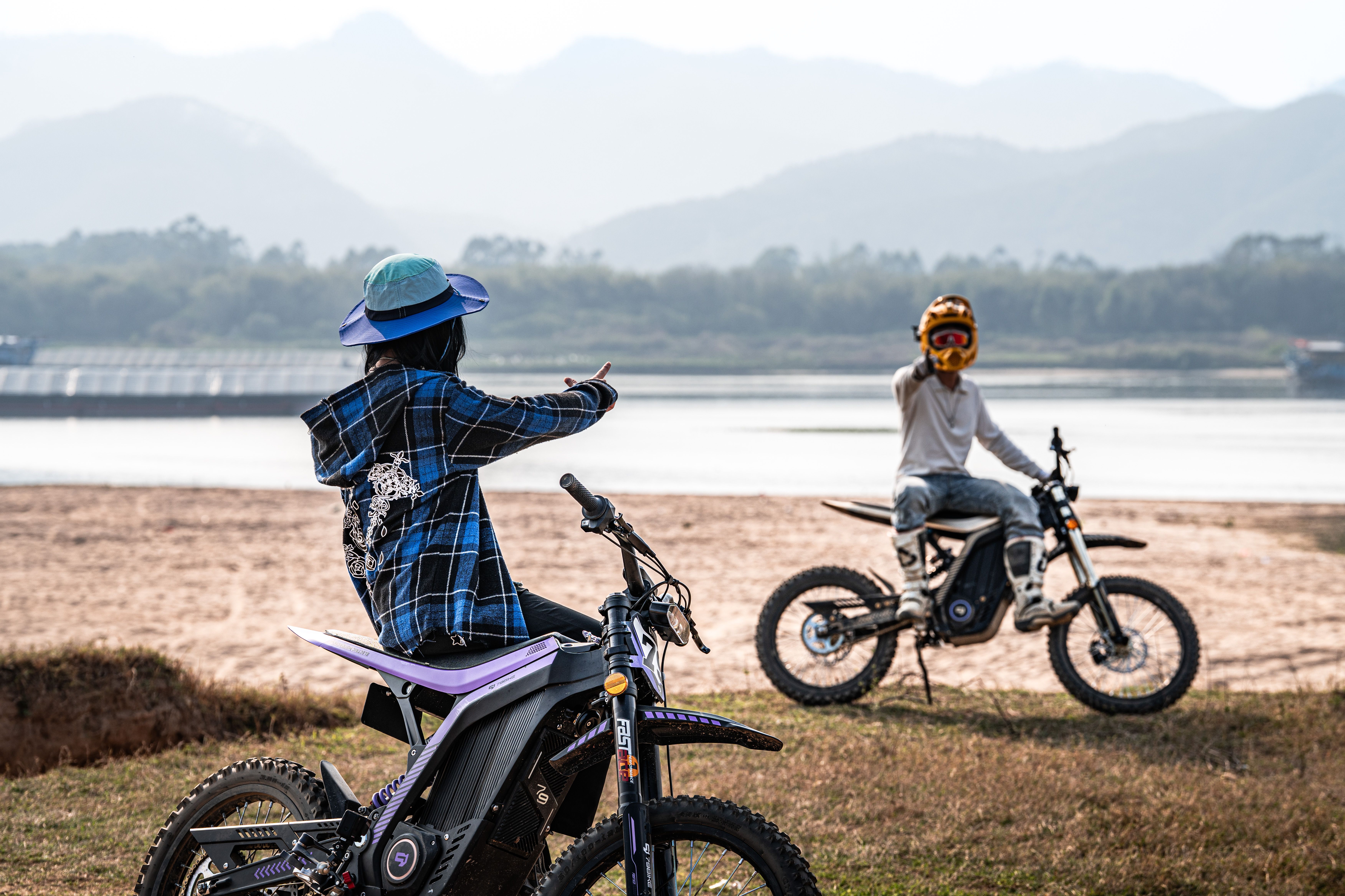 Two motocross riders near lake with mountains