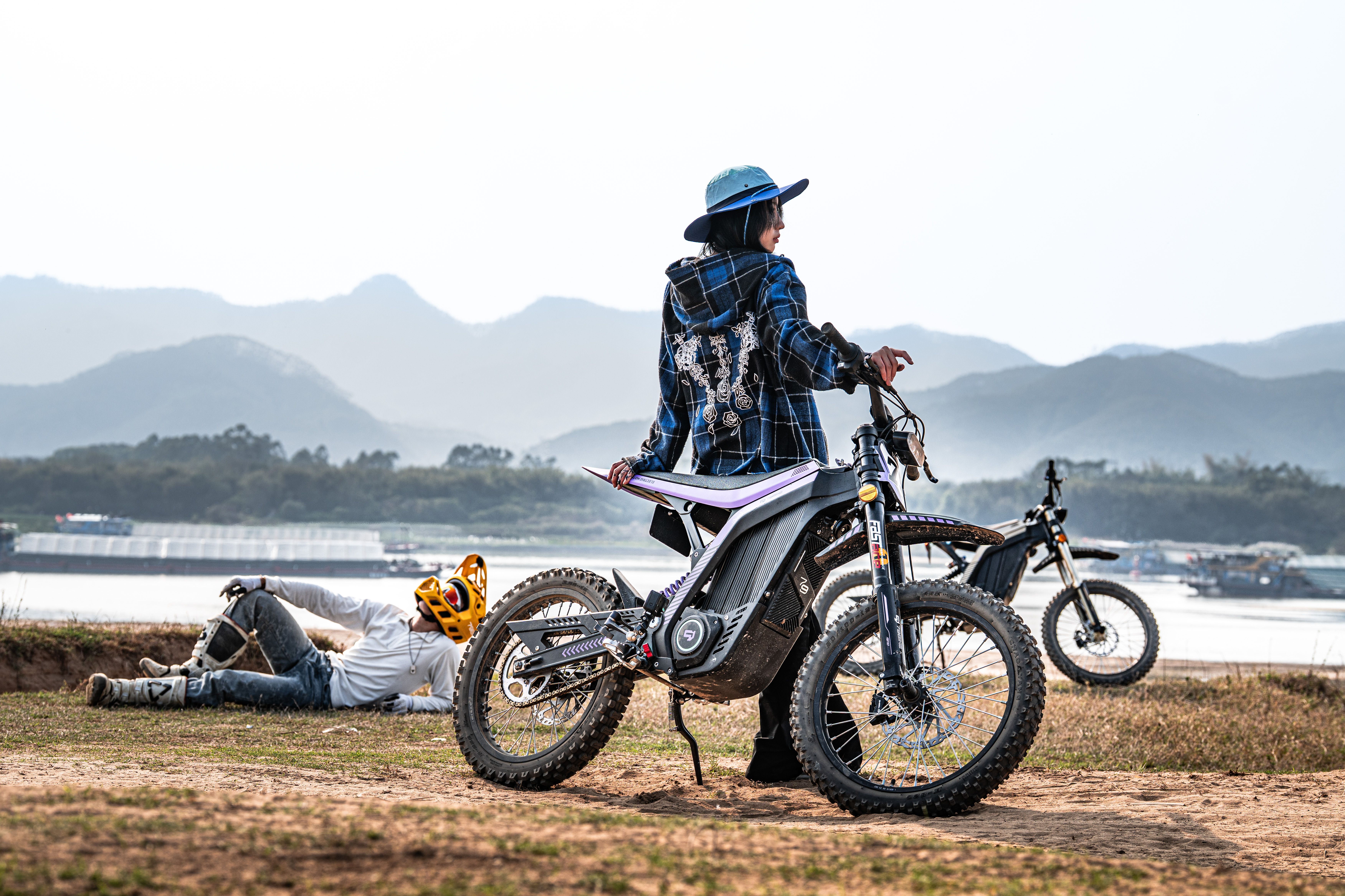 Two dirt bikers with bikes near mountain lake