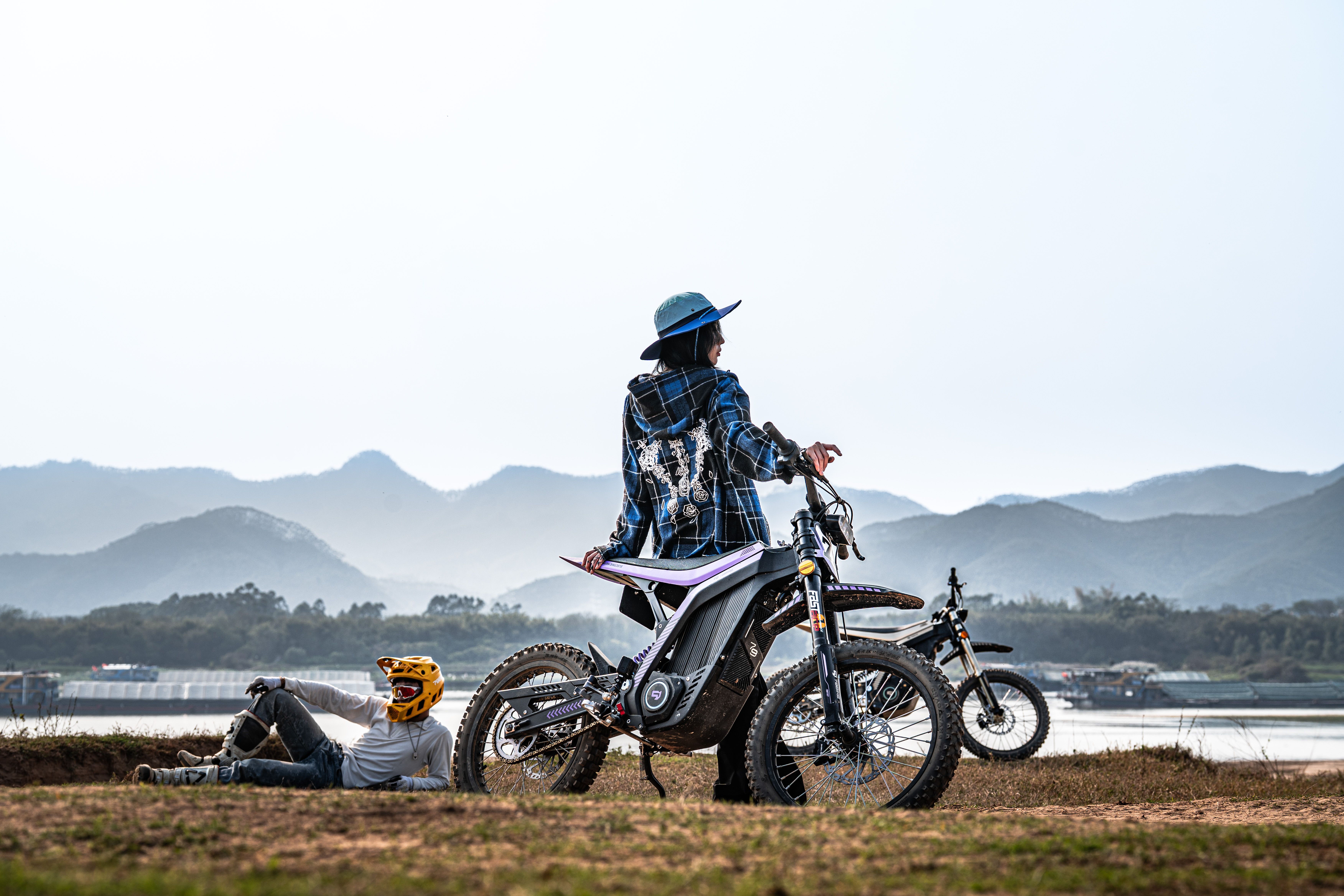 Two motorcyclists relaxing outdoors with mountains